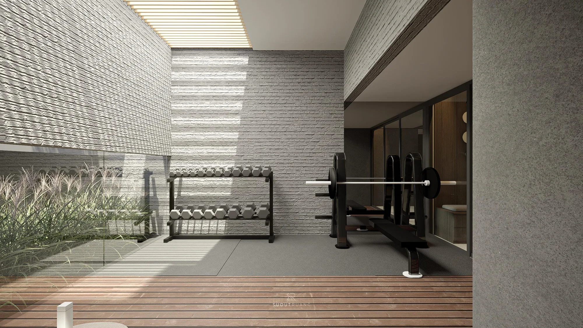 A two-tier dumbbell rack and loaded barbell bench sit against white-washed brick beneath the skylight, frameless glass separating the gym from planted ornamental grass.