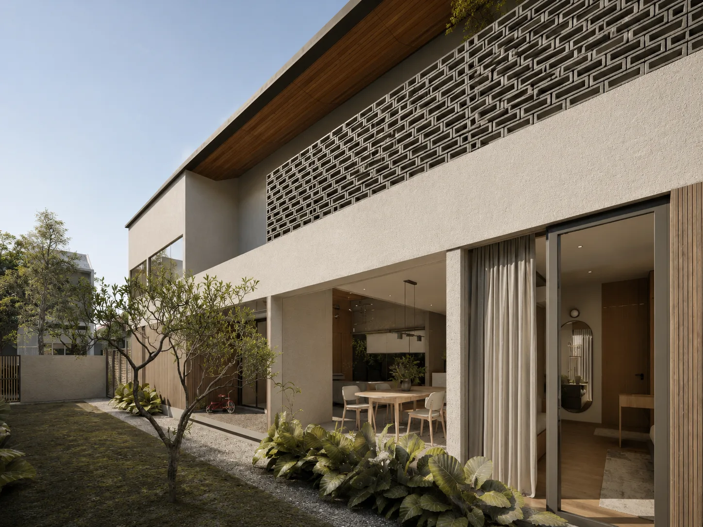 Perforated brick screen above a plastered wall, with a sliding glass door opening the dining area to a gravel side garden.