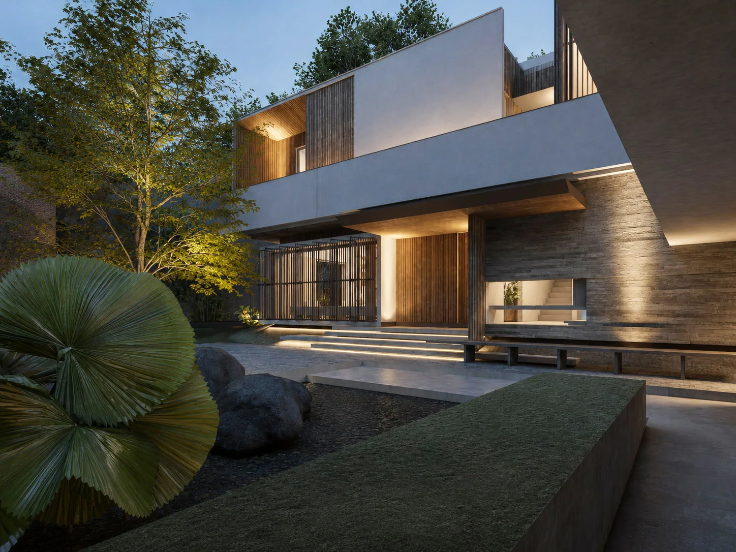 Evening view of the entry courtyard, uplit stone walls and a timber-screened porch beside a raised lawn planter and boulders.