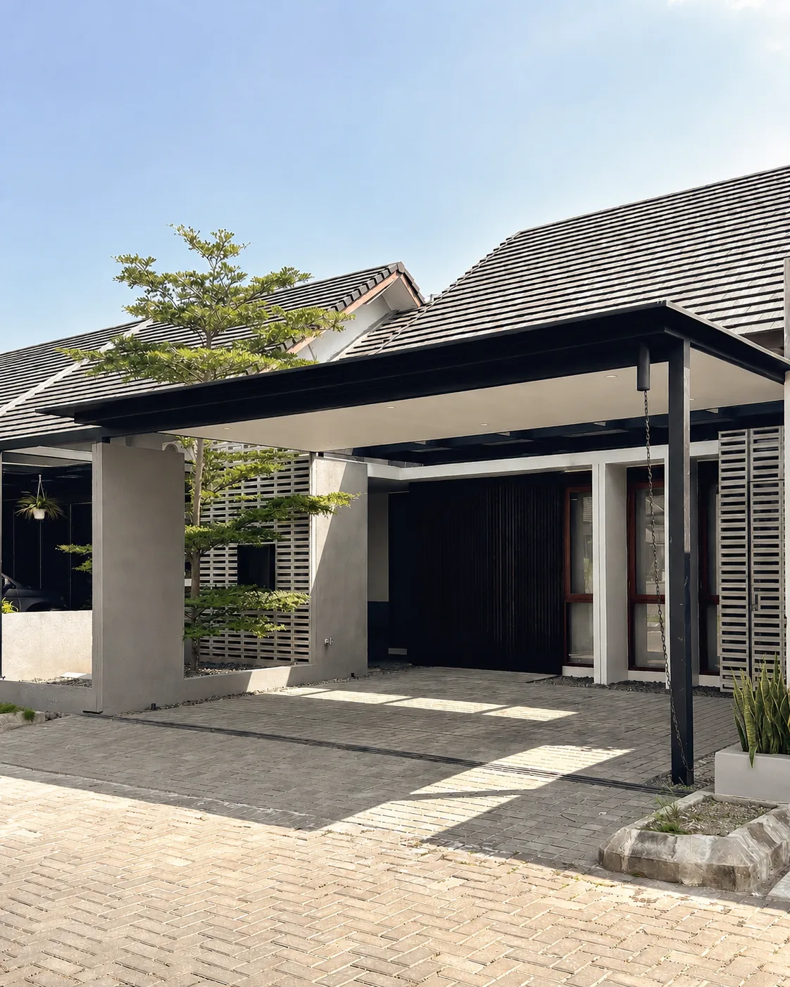 Kiwari House's carport beneath a tiled roof overhang, a timber slat screen and dark entrance door behind the canopy.