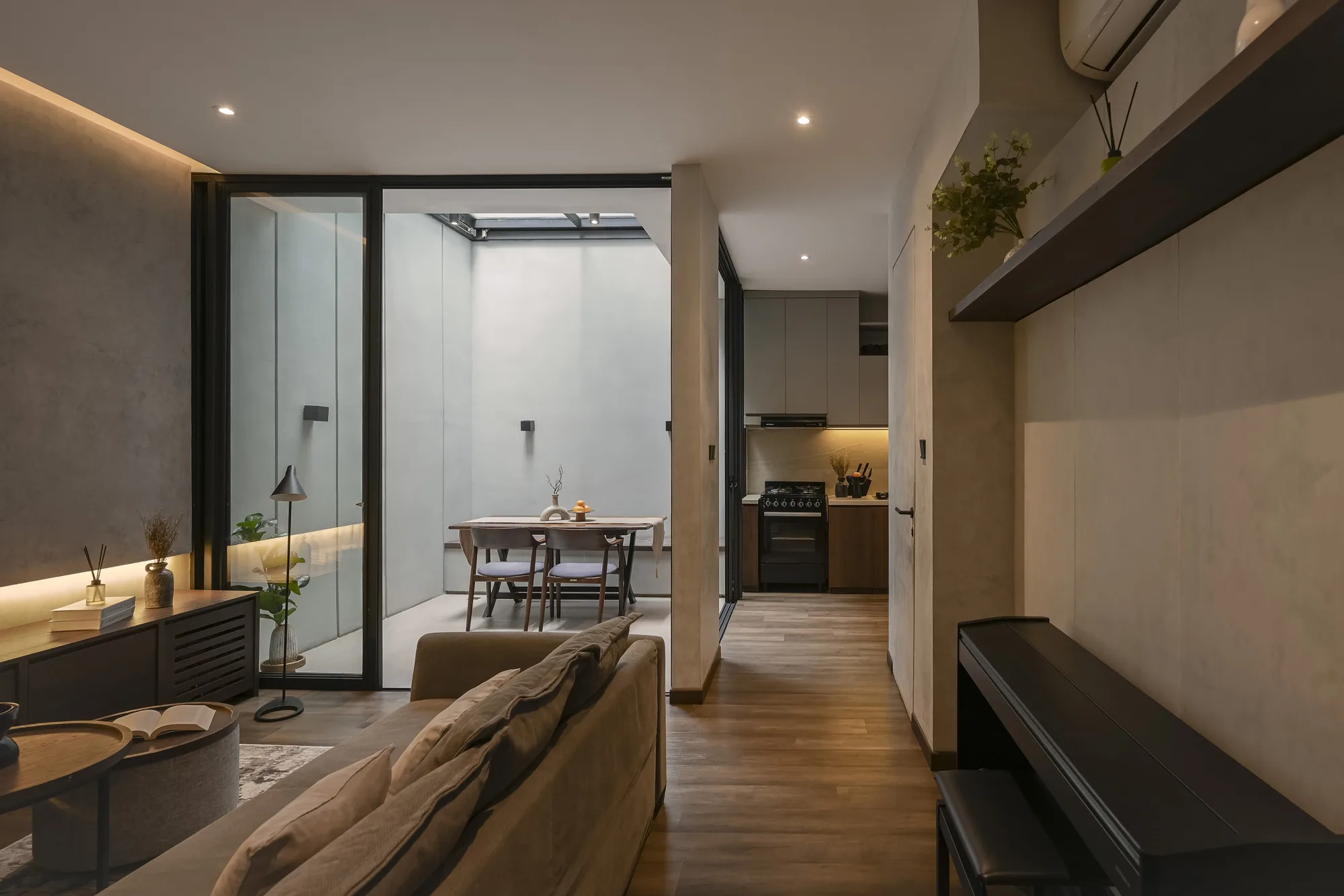 Living room opening past a concrete-look wall to the retractable-roof dining area, with the kitchen down the corridor.
