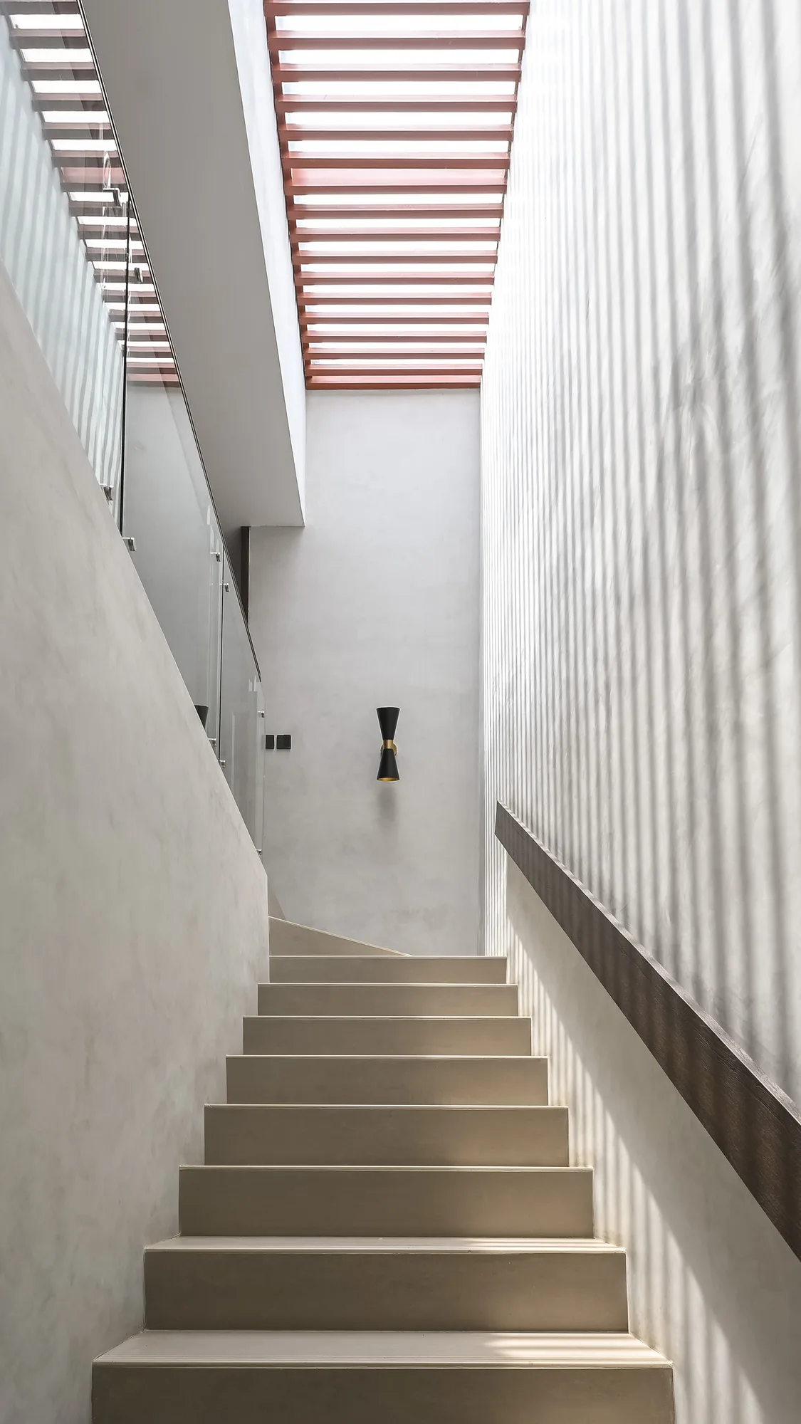 Stairwell rising past a timber slat screen toward the retractable roof's battened cover.