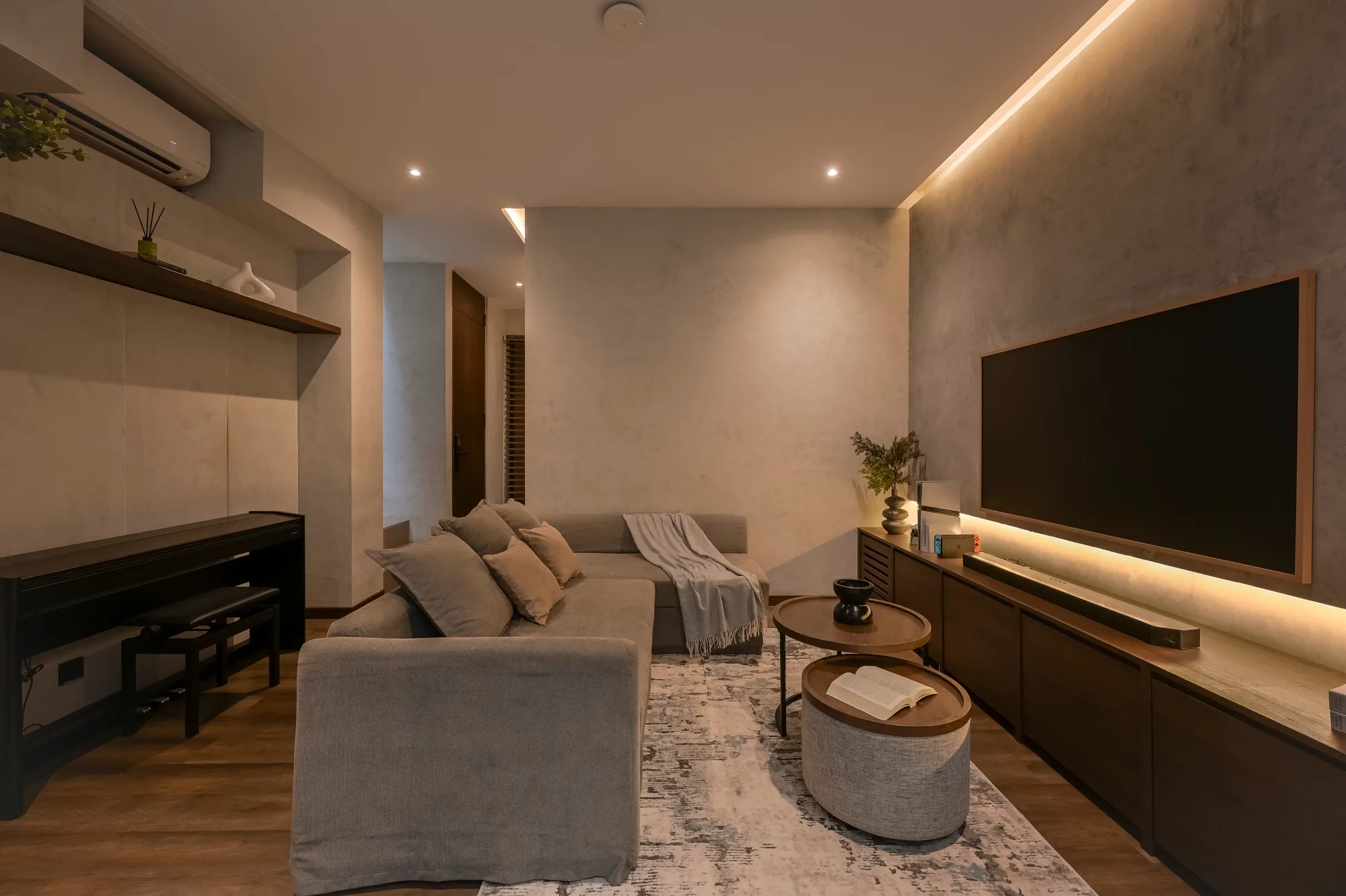 Living room sofa facing the concrete-look wall and its recessed television.