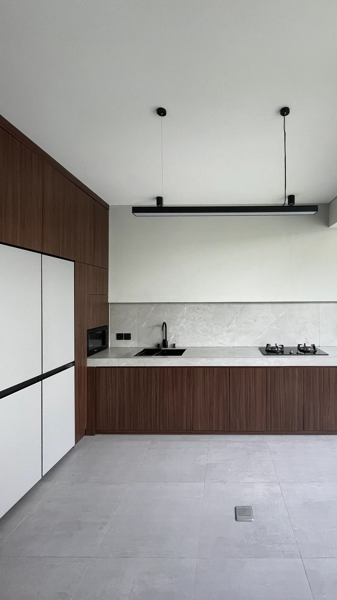 The kitchen, a white refrigerator and dark wood cabinetry along one wall, sink and hob along the counter.