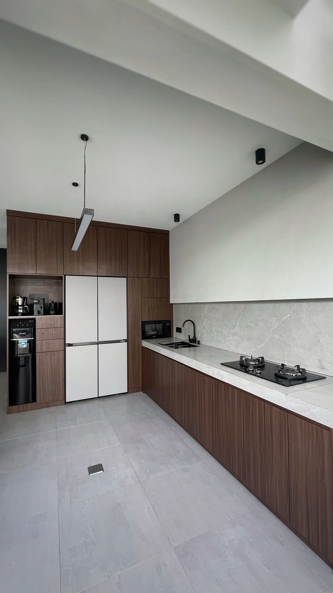A coffee station and water dispenser built into the kitchen cabinetry beside the refrigerator.