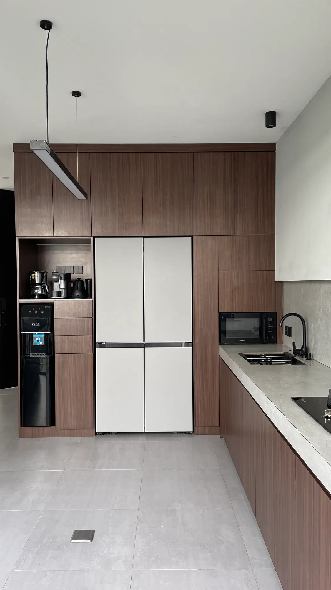 The kitchen's white refrigerator and dark wood cabinetry, a pendant light bar overhead.