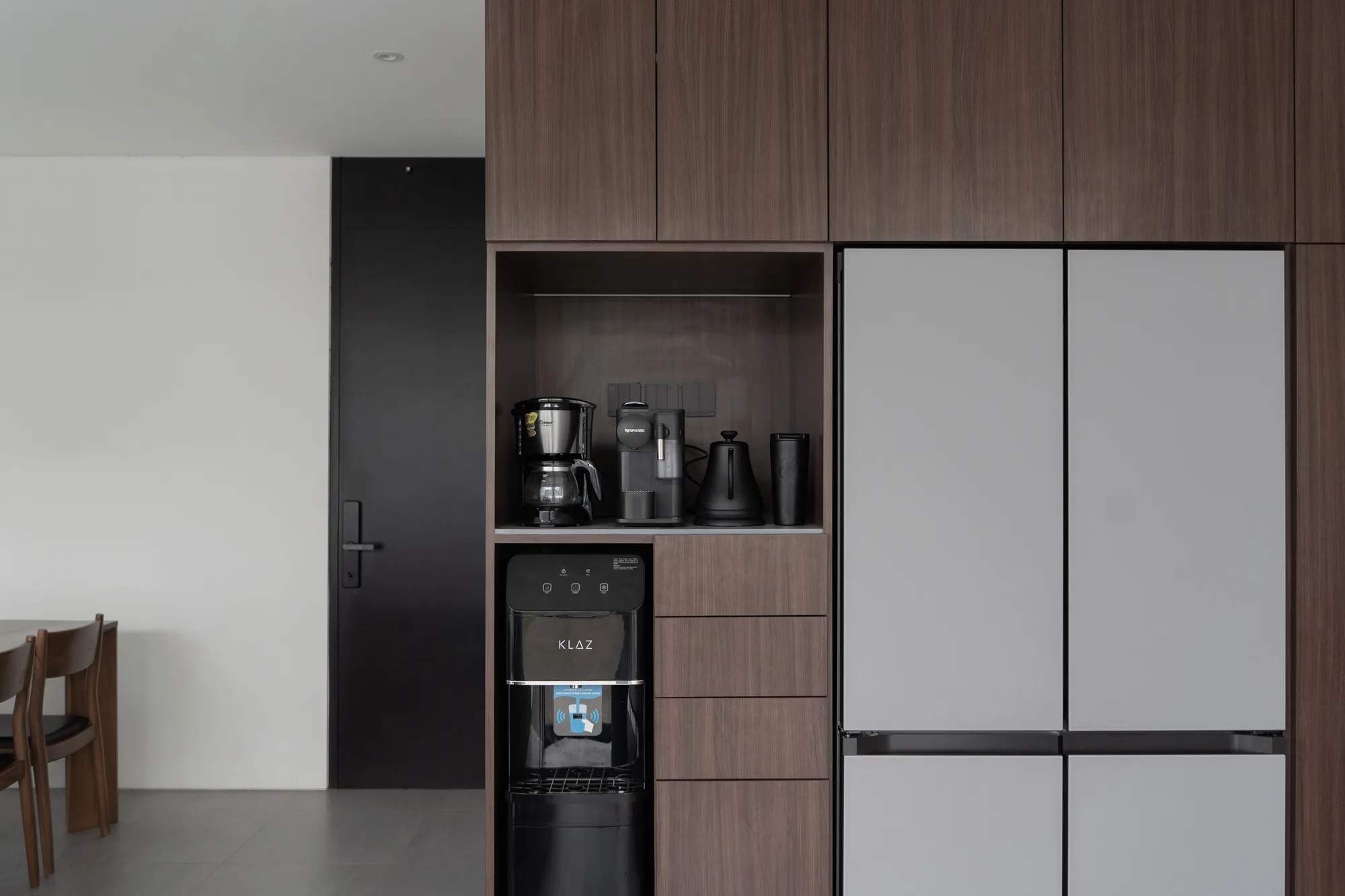 The kitchen's coffee and water-dispenser nook beside the refrigerator, seen close.