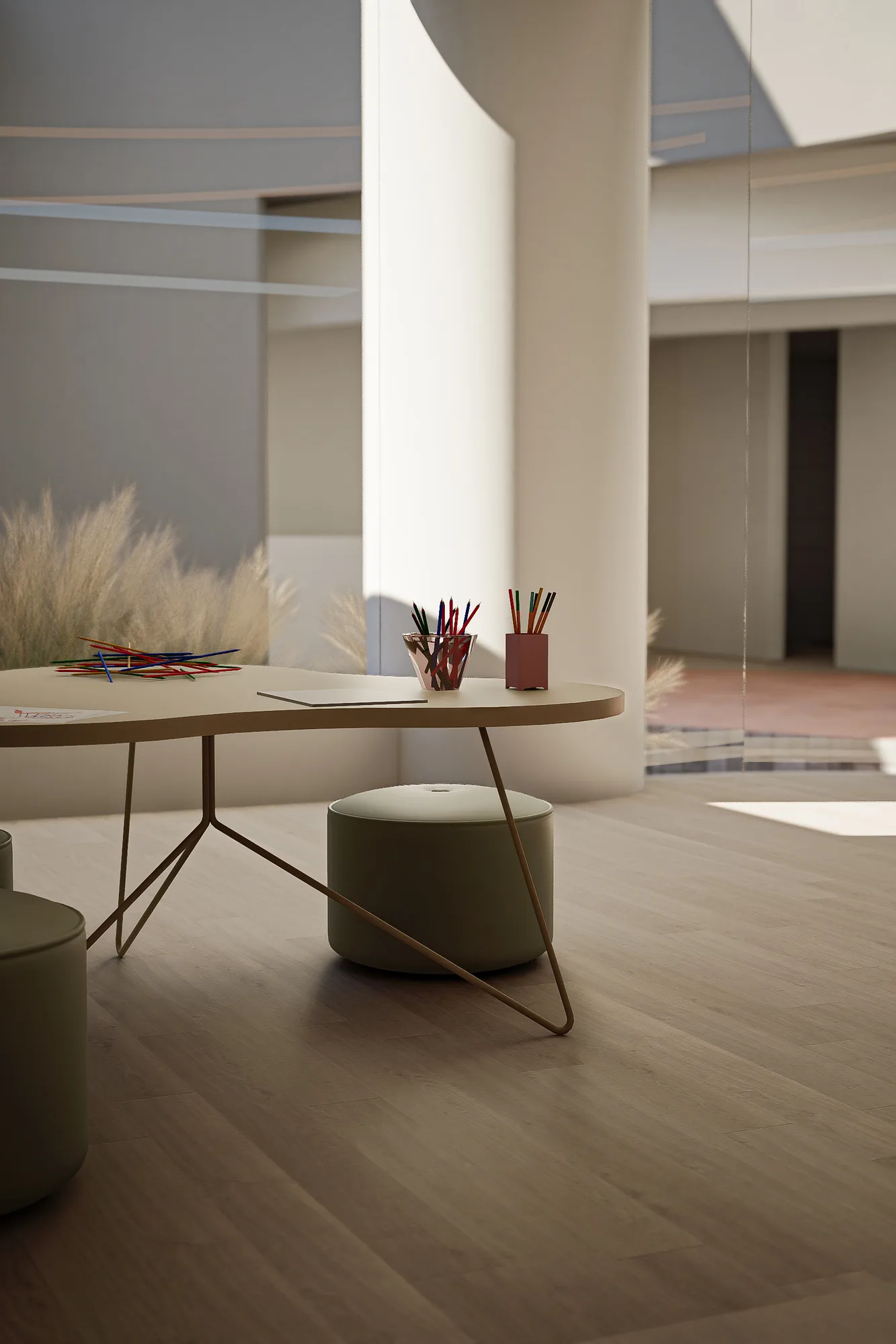 Children's play table with colored pencils and building sticks beside a curved white column in the daycare space.