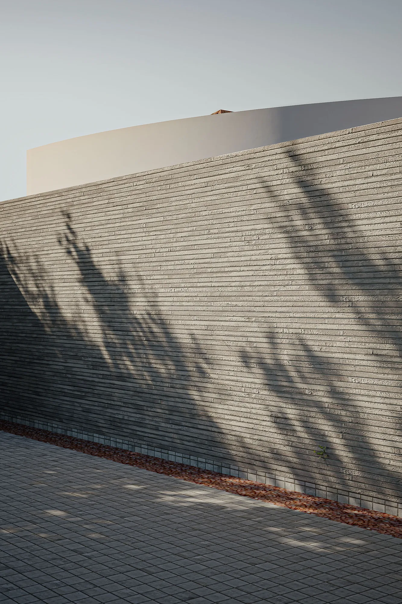 Front approach to Pilates and Daycare showing the curved white upper volume rising above the ribbed concrete perimeter wall.
