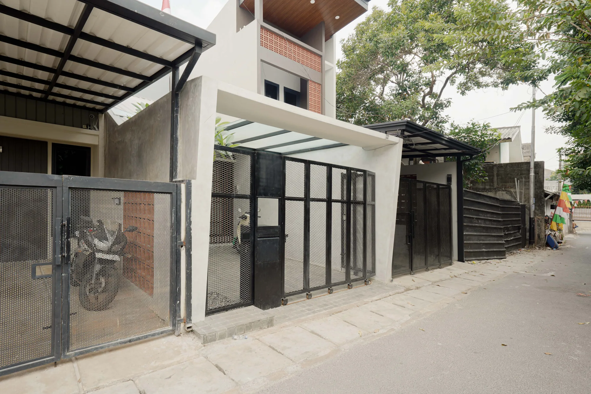 Angled street view of Prada House, its pale facade and black steel gate opening onto a narrow neighborhood lane.