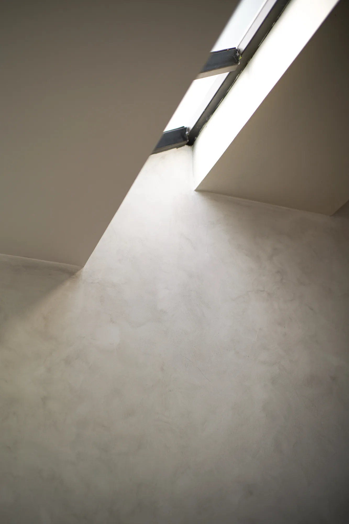 Angular skylight opening washing a pale plaster wall with daylight.