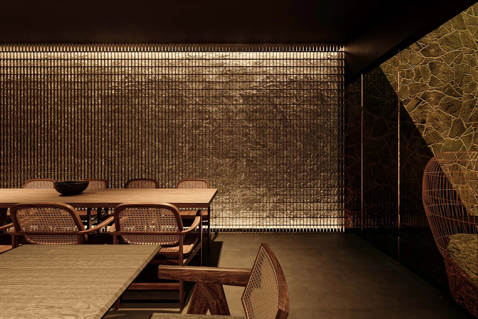 Private dining table with cane armchairs, lit against a backlit brass slat wall and a rough stone corner.