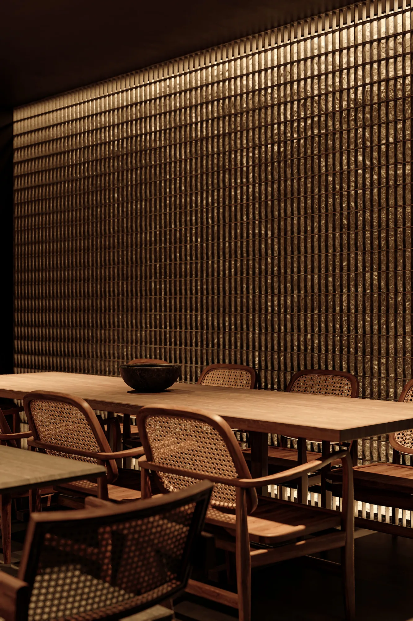 A closer view of the same table against the backlit brass slats, a woven rattan pendant just visible at the edge.