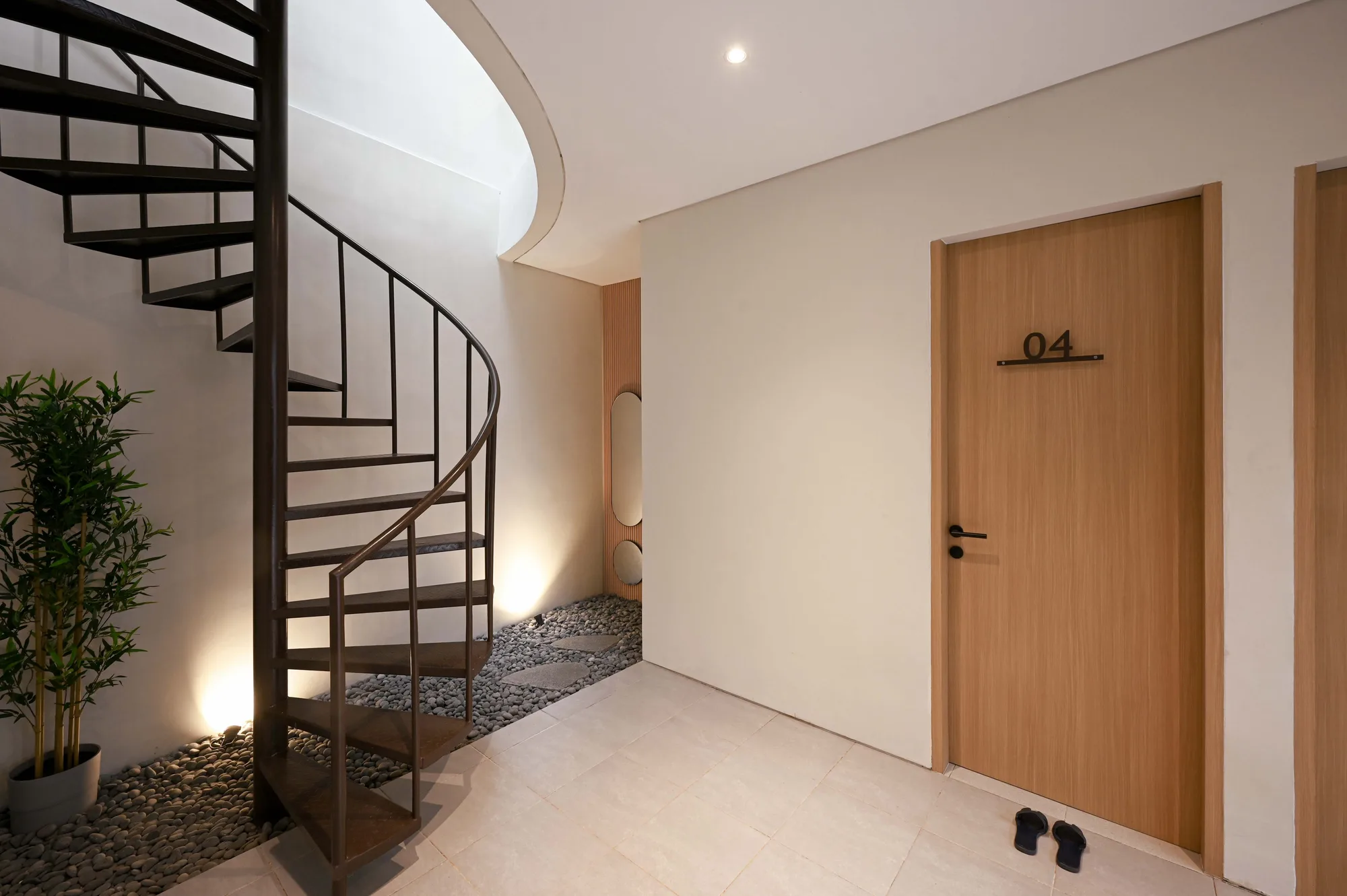 Interior corridor at the base of the spiral stair, with a mirrored niche and door 04 opening off the tiled landing.