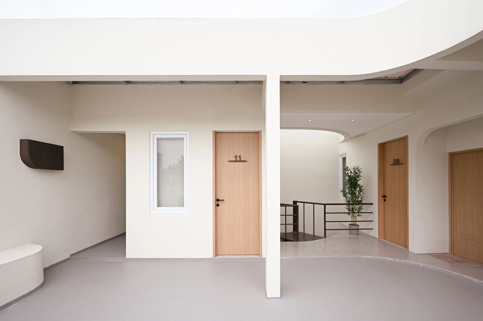 Room 11's door beside the void, with the spiral stair and room 09 visible one level down through the open curve of the building.