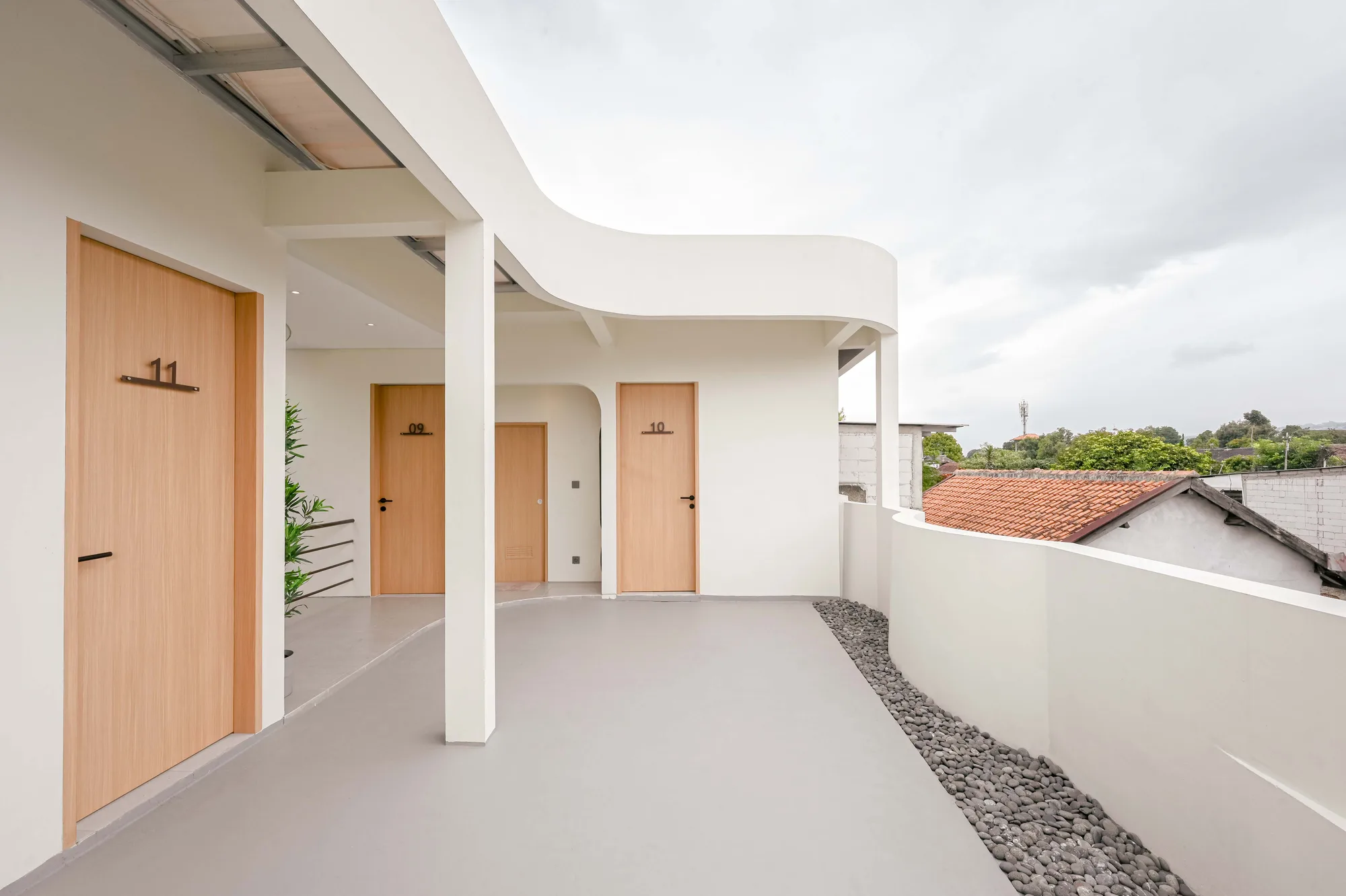 Rooftop-level corridor curving past room doors 09 and 10, with a red-tiled neighboring roof visible beyond the low parapet.