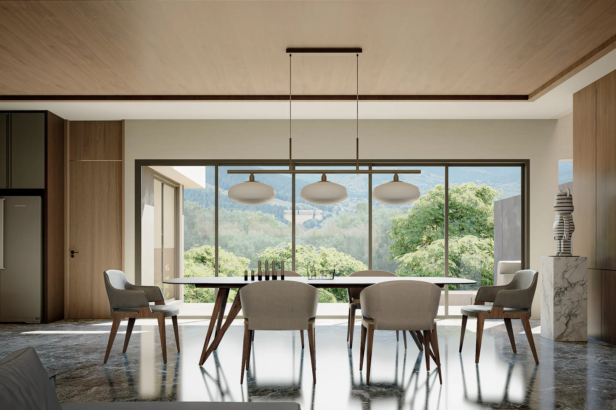 Dining table set beneath a linear brass pendant, full-height glass framing a forested hillside view.